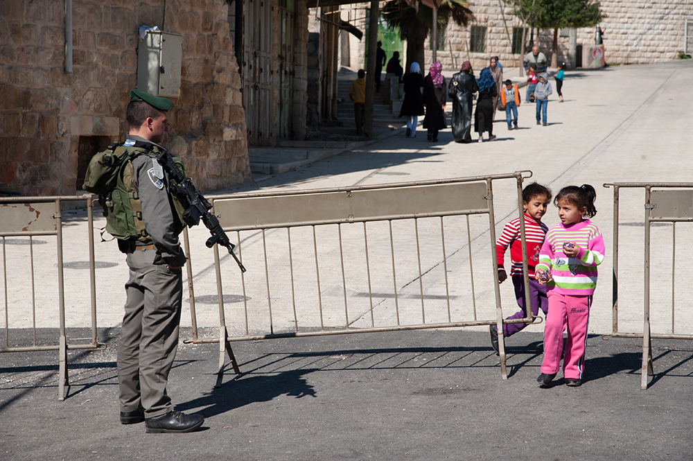 Two young Palestinian girls walking through an Israeli checkpoint in the West Bank during their daily routine.